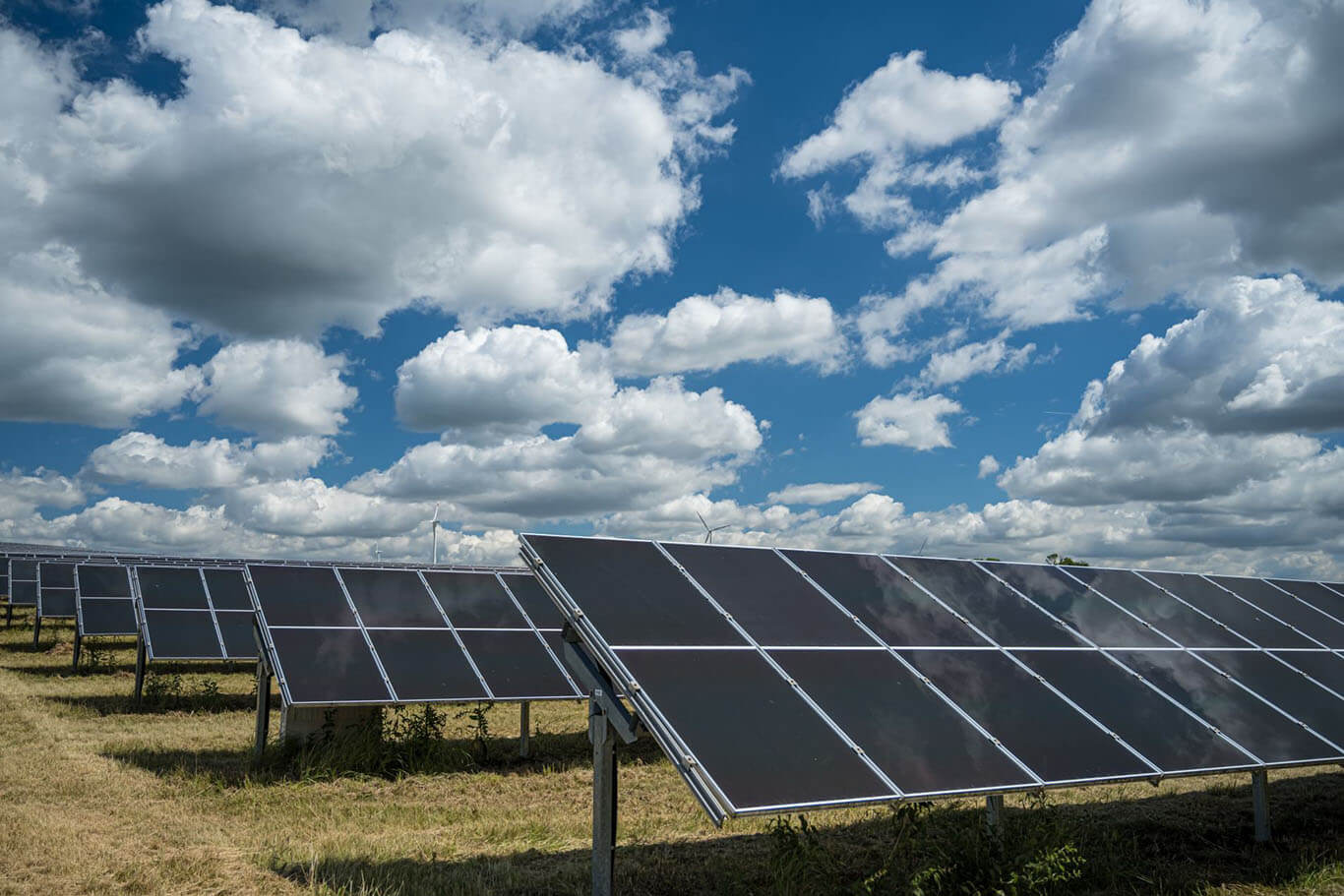 Ground-mounted solar farm with photovoltaic panels under a cloudy sky