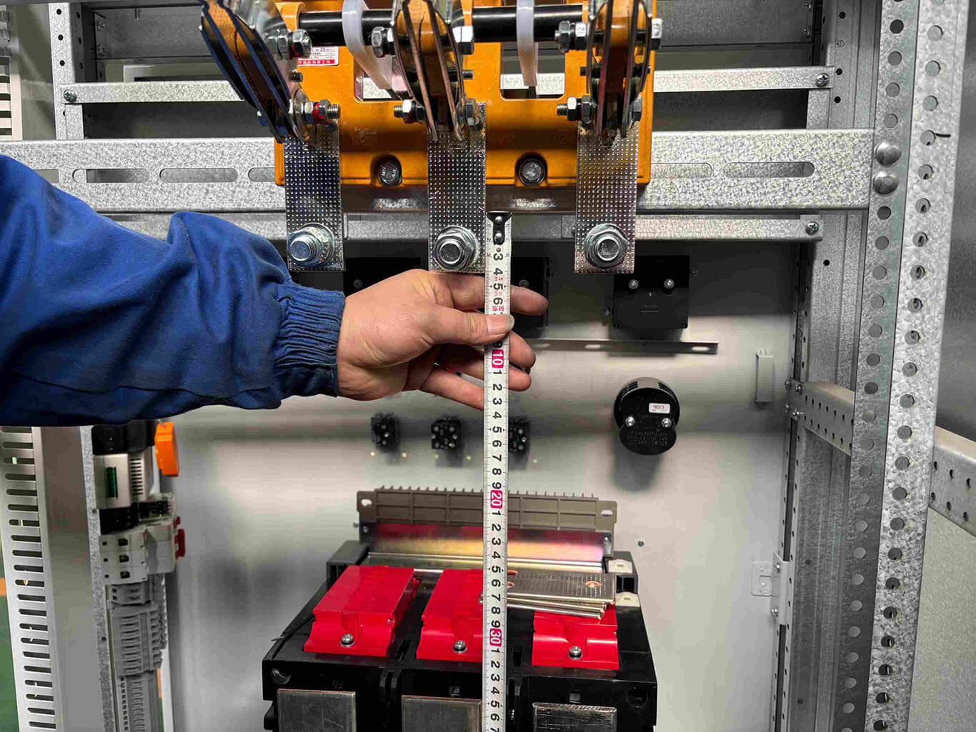 The worker is measuring the length of the copper busbar